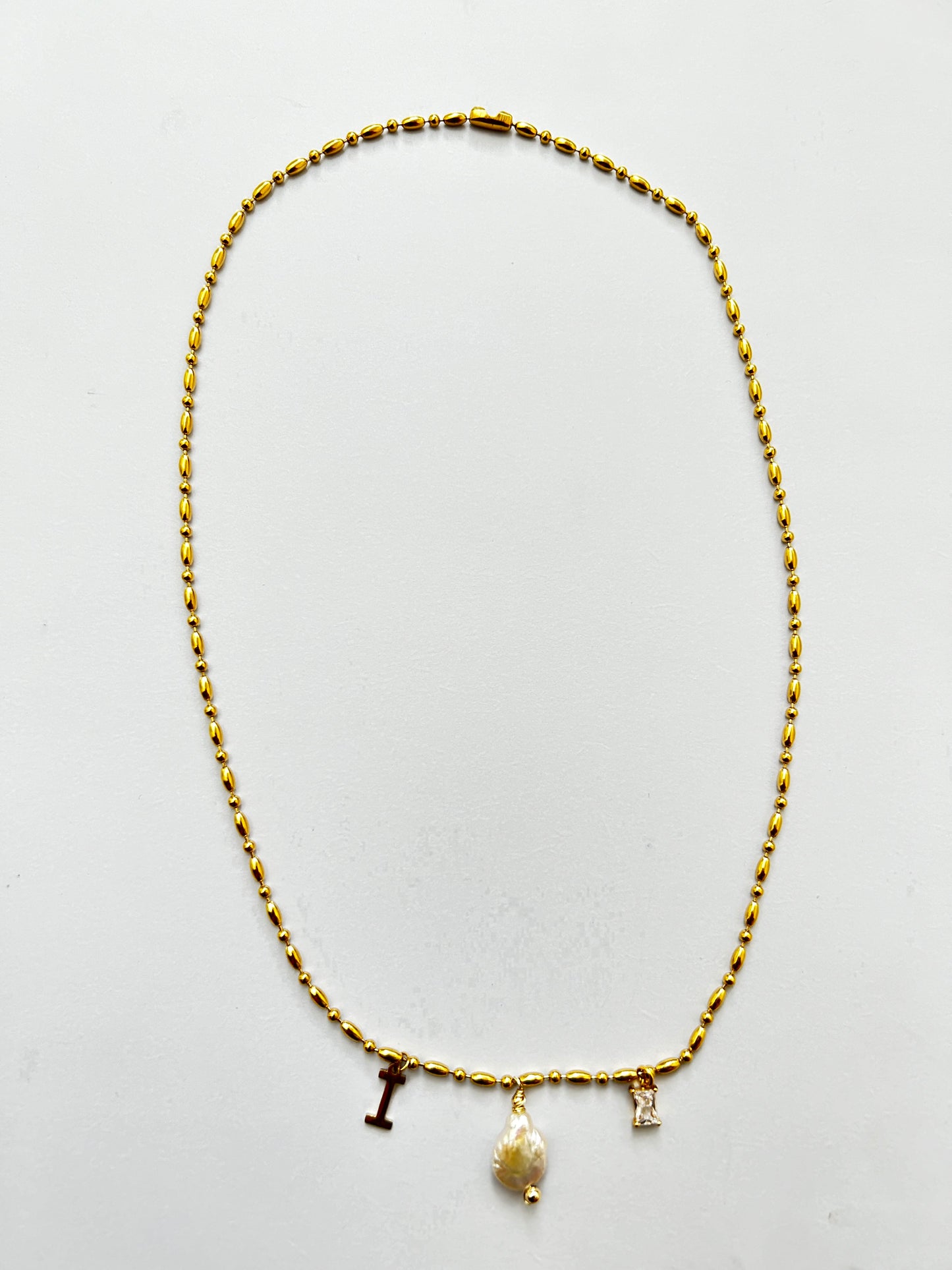 Cadena dorada con perla, inicial y joya